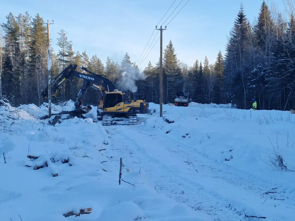 Kaivinkone pylvästää sähkölinjaa.